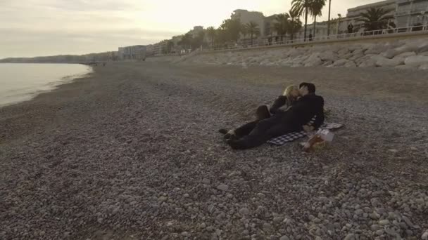 男性と女性の夜キス、ロマンチックなニースの海辺で毛布の上に横たわる — ストック動画