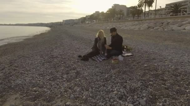 Verliebte Männer und Frauen picknicken am Meer, öffnen eine Flasche Wein, verabreden sich — Stockvideo