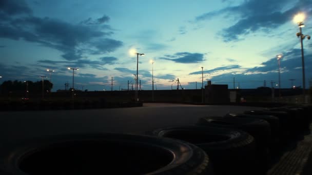 Circuito di go-kart all'aperto con auto che passano sotto il cielo blu scuro della sera, time-lapse — Video Stock