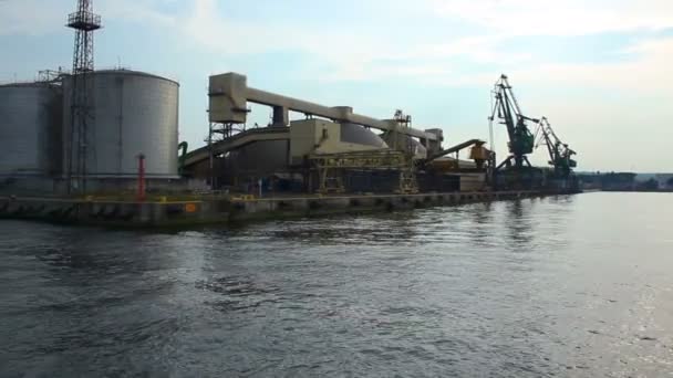 Вид на величезні склади і портові крани з човна, що рухаються повз, транспорт — стокове відео