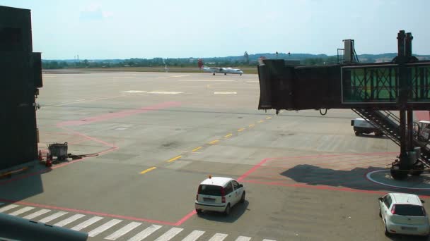 Avión moviéndose a través del área de estacionamiento señalizada, acercándose a una pasarela de embarque — Vídeo de stock