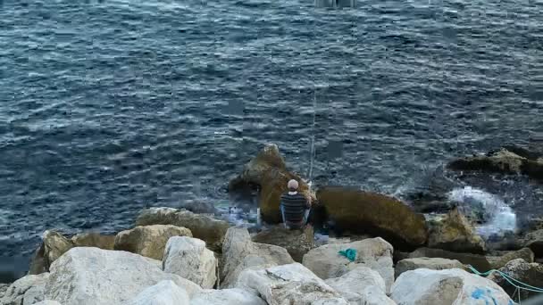 Рибалка сидить на величезних каменях і риболовлі, хобі і релаксації, відпочинку — стокове відео