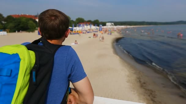 Homem turista olhando para adultos e crianças relaxando e brincando na praia, viagens — Vídeo de Stock