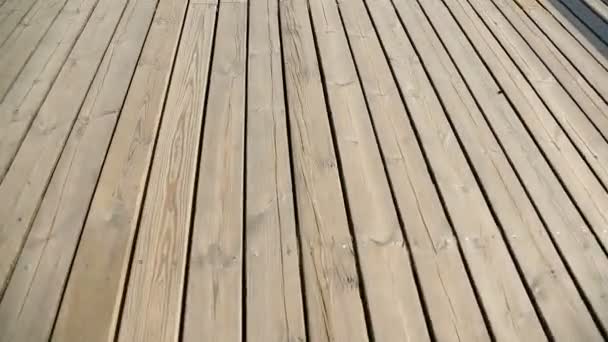 Persona caminando a lo largo del muelle de madera y mirando hacia abajo, amarre junto al mar para los buques — Vídeo de stock