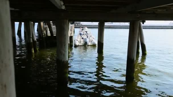 Lancha amarrada en el viejo muelle de madera, la gente sale del barco después del tour de pesca — Vídeos de Stock