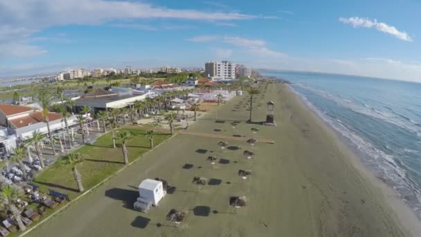Вид с воздуха на пляж с соломенными зонтиками и шезлонгами в городе Ларнака — стоковое видео