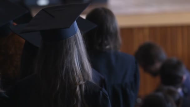 Feliz día de graduación, estudiantes en mantillas y gorras esperando diplomas — Vídeo de stock