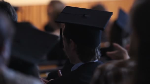 Ενθουσιασμένος απόφοιτος σε mortarboard χειροκροτούν Πρυτανικού ομιλία στην τελετή αποφοίτησης — Αρχείο Βίντεο
