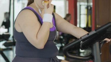 Spor salonunda egzersiz sırasında donut yemek zayıf irade ile obez genç kadın
