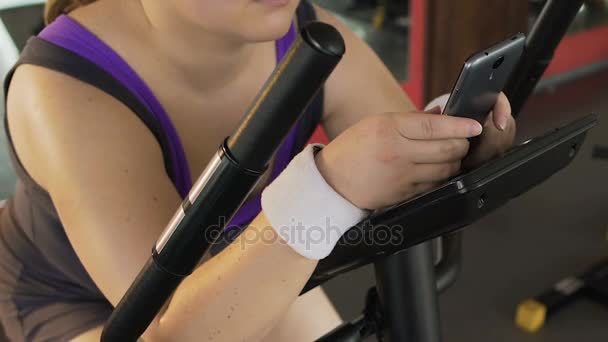 Woman lazily turning simulator pedals without applying any effort to lose weight — Stock Video