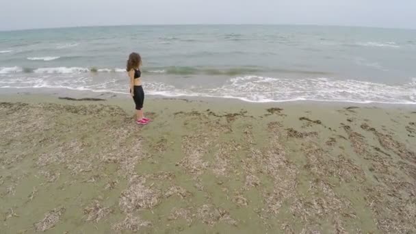 Брюнетка тренируется на песчаном пляже, делает приседания, спорт и здоровье — стоковое видео
