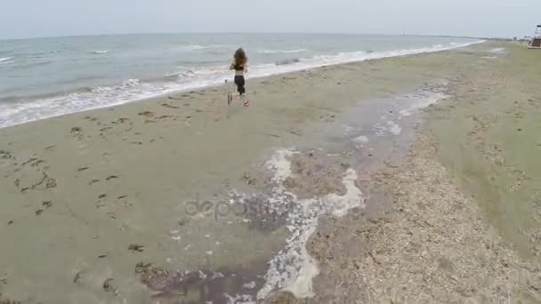 Smal kvinna löper längs tom beach, utbildning och njuta av utsikten, antenn skott — Stockvideo
