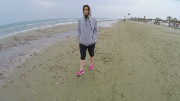 Treurige vrouw in sportkleding wandelen langs strand en denken over vriendje — Stockvideo