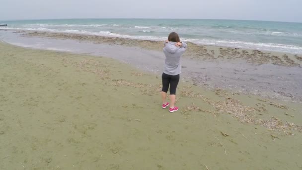 Mooie dame met krullend haar genieten van prachtig uitzicht op zee, staande op het strand — Stockvideo