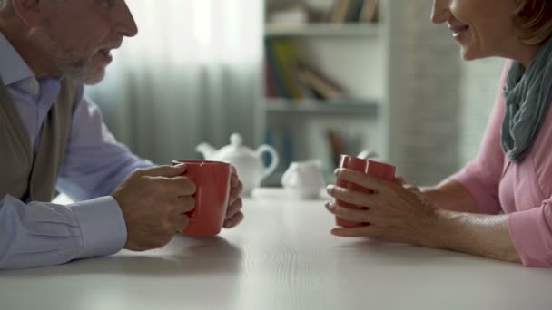 Letitý muž a žena mluvila přes šálek čaje u stolu, školní bráškové, setkání — Stock video