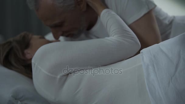 Ηλικιωμένοι άνδρες και γυναίκα ξαπλωμένη στο κρεβάτι και αγκαλιάζει, άνδρας γυναίκα φιλιά απαλά — Αρχείο Βίντεο