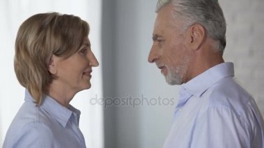 Yaşlı kadın ve erkek birlikte, alınlarına koyarak birbirine, mutlu bakarak