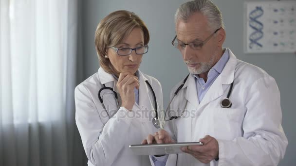 Médico masculino mostrando tablet para sua colega, história médica eletrônica — Vídeo de Stock