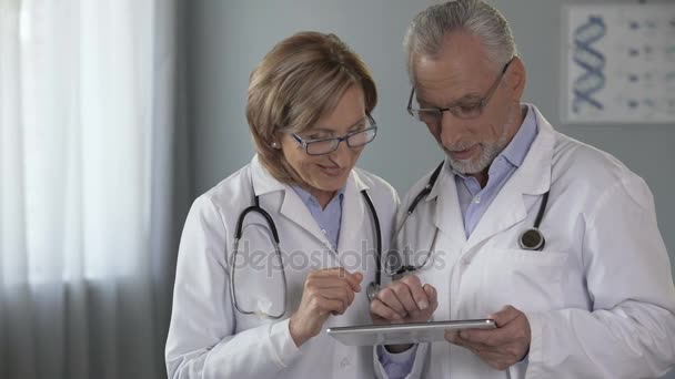 Női és férfi orvosok nézett csodálattal tabletta, app orvosok — Stock videók