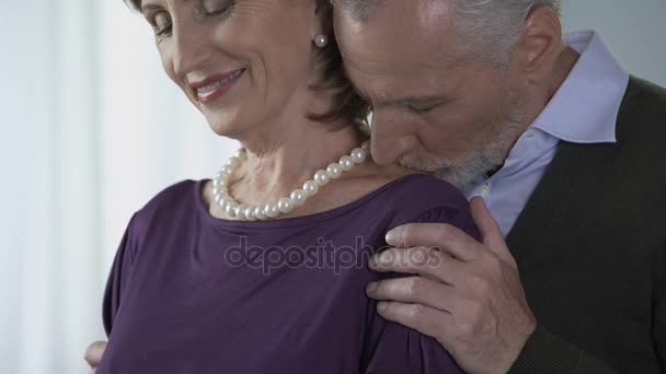 Літній чоловік цілує жінку в перлах на плечі, особливий випадок, щастя — стокове відео