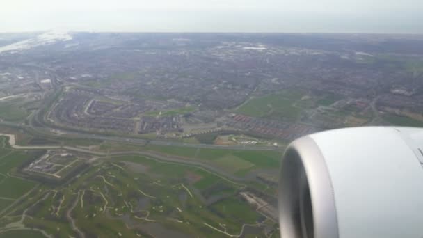 Plane engine seen through window, green fields below flying aircraft, travel — Stock Video