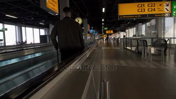 Viajero masculino con la maleta moviéndose en la escalera mecánica del aeropuerto a la puerta, vacaciones — Vídeo de stock