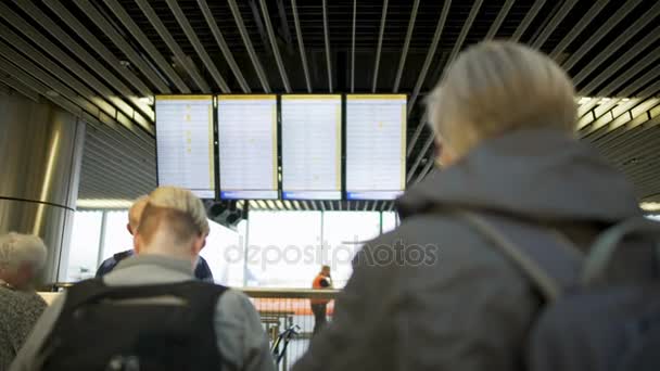 Пасажири аеропорту, які дивляться на дошку відправлення і чекають на літак, термінал — стокове відео