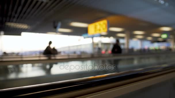 Rozostřeného eskalátoru na letišti, cestující řítí k bráně, doprava — Stock video