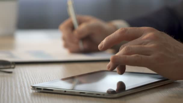 Τα χέρια του επιχειρηματία ζουμ στο tablet, εργαζόμενος γραφείου, καθιστώντας τις σημειώσεις στο γράφημα — Αρχείο Βίντεο