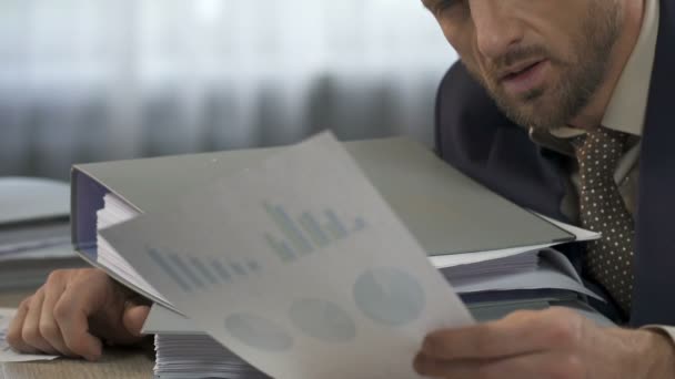 Homme fatigué assis à la table et regardant les statistiques d'entreprise, crise au travail — Video