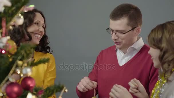 Inspirados por el humor de celebración familia decorando el árbol de Navidad juntos en casa — Vídeo de stock