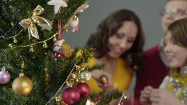 Padres amorosos ayudando a su hija a decorar el árbol de Navidad, momentos mágicos — Vídeos de Stock
