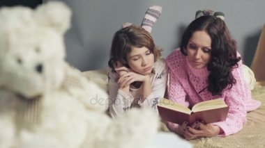 Anne ve kızı rahat yatakta yatarken, masal okuma ve rüya