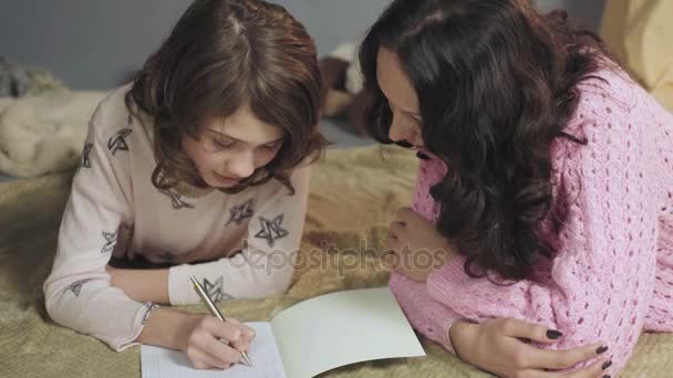 Дочь делает домашнее задание, разговаривает с матерью о дне в школе, семье — стоковое видео