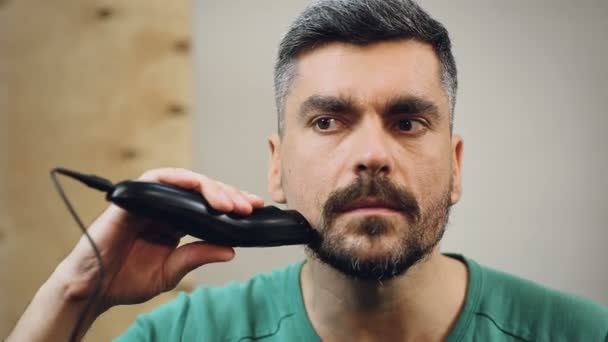自信を持って男性の電気シェーバーは、個人的なスタイルを変更すると彼のあごをシェービング — ストック動画