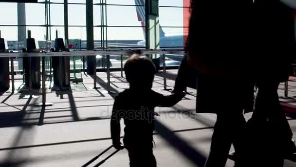 Silhouette di persone che attraversano il terminal illuminato dal sole, viaggiano in aereo, rallentano — Video Stock