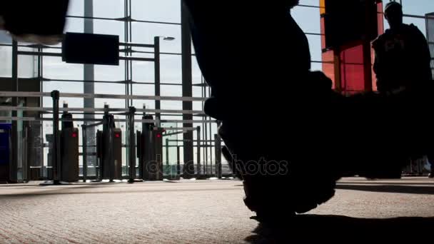 Silhouetten von Menschen, die am Terminal des Flughafens an den Gates vorbeigehen, Flug, Blick von unten — Stockvideo