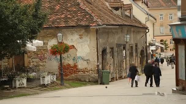 Toeristen wandelen in de prachtige oude straat met rode dak gebouwen, stad van Zagreb — Stockvideo