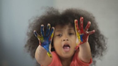 Neşeli Afro-Amerikan kız eğleniyor ve gösterilen avuç içi kameraya boyalı.