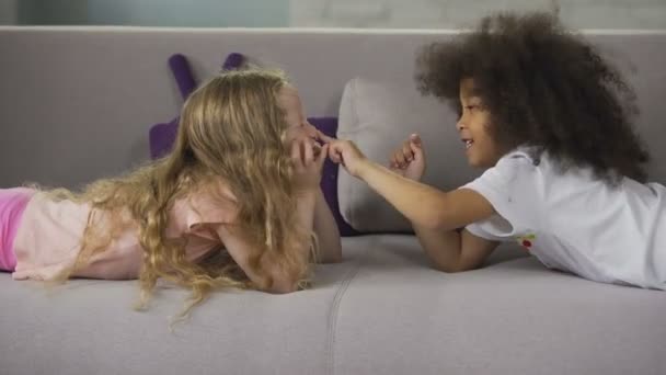Söta multiracial bästa vänner liggande på soffan och att ha kul, barndom och glädje — Stockvideo