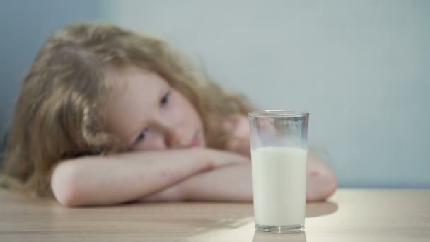 Trauriges weibliches Kind sitzt am Tisch und schaut auf ein Glas Milch, Frühstück — Stockvideo