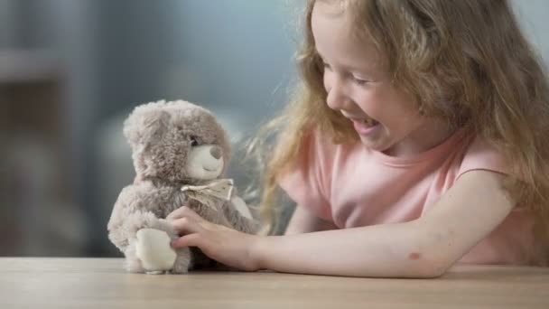 Chica rubia alegre jugando con el oso de peluche y riendo, actividad de ocio — Vídeos de Stock