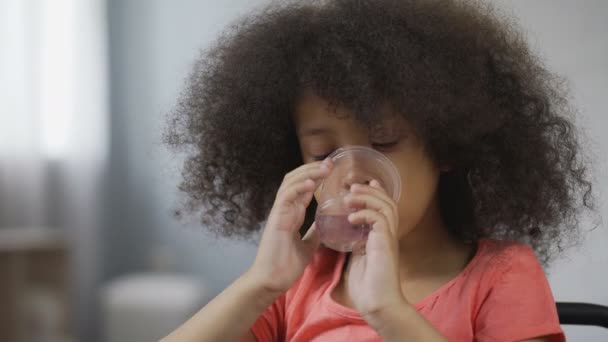 Thirsty Afro-American kid drinking still mineral water, close-up of child's face — Stock Video