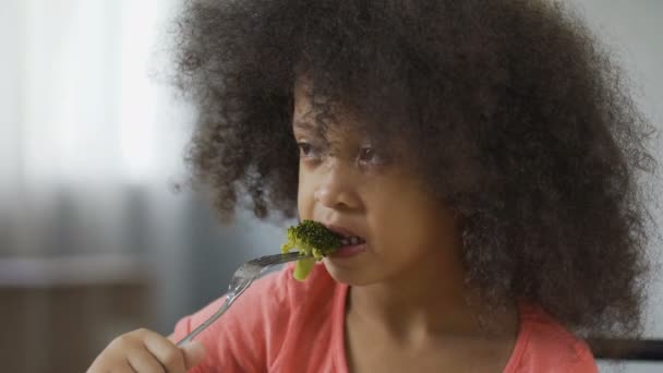 Divertente ragazza afroamericana che mangia broccoli con disgusto, cibo sano, dieta — Video Stock