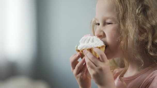 Крупный план красивой маленькой девочки, кусающей торт и наслаждающейся идеальным вкусом десерта — стоковое видео