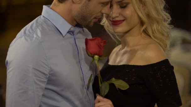 Ρομαντική ημερομηνία δύο ελκυστικά άτομα, γυναίκα κρατώντας τριαντάφυλλο και φιλιά φίλο — Αρχείο Βίντεο