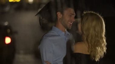 Mutlu gülümseyen adam ve yağmur altında sarılma ve taksi için bekleyen kadın tarihi