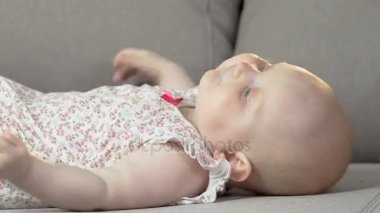 Kollar ve bacaklar, enerjik çocuk, bebeklik tekme kanepenin arkasında yatan bebek