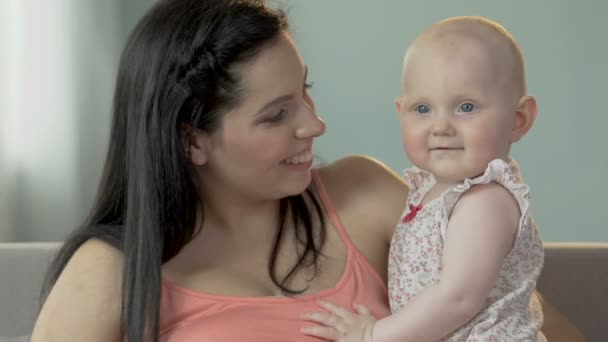 Jovem fêmea segurando e tocando bebê menina com nariz, criança abraçando-a, amor — Vídeo de Stock