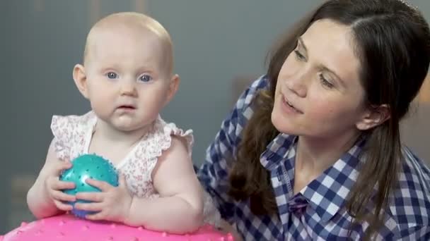Frau hält Kleinkind auf Fitnessball, tingelt auf und ab, verspieltes Baby — Stockvideo
